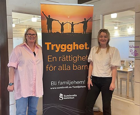 Två kvinnor står framför en rollup med texten Trygghet. En rättighet för alla barn. Bli familjehem! www.sundsvall.se/familjehem Sundsvalls kommun.