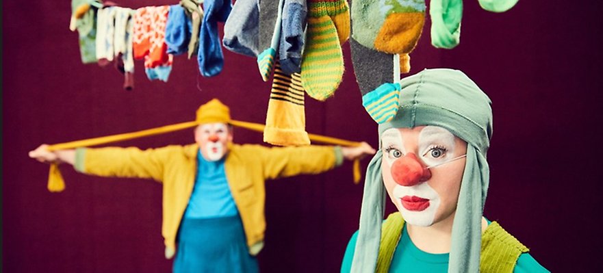 Två clowner under ett klädstreck fullt med strumpor. 